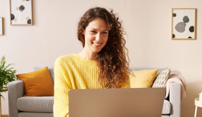 Norton Safe Search'ü dizüstü bilgisayarında başlatırken gülümseyen kadın.