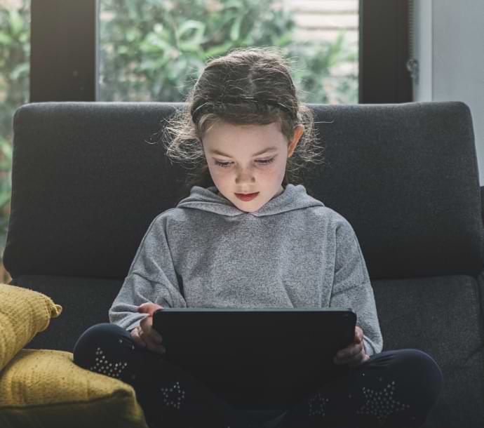 Norton Aileyi başlatan dizüstü bilgisayarı kullanırken kanepede oturan kız.